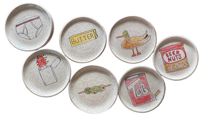Set of ceramic plates with various illustrations on a wooden surface